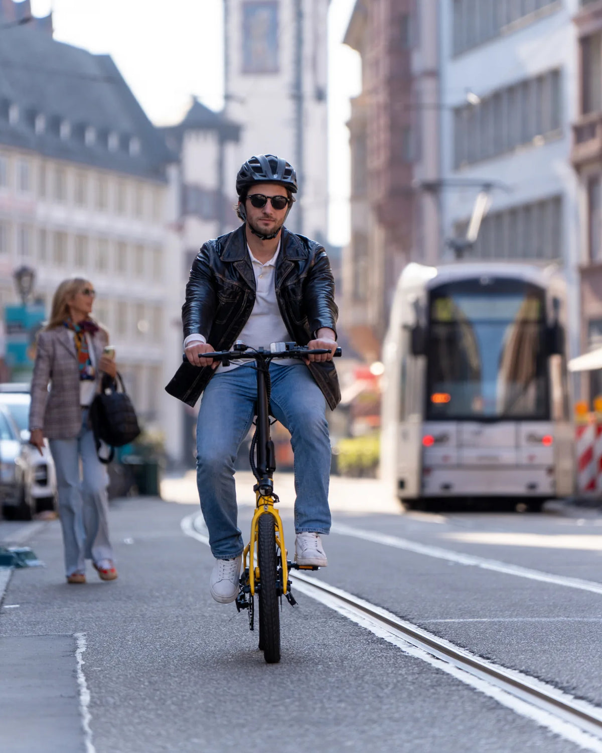 Mann fährt mit einem gelben Cyseekin E-Bike neben einer Straßenbahn